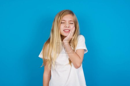 Photo for Beautiful caucasian girl wearing t-shirt  with toothache on blue - Royalty Free Image