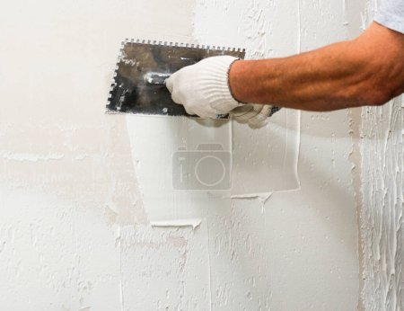 Golpeando la clavija contra la pared. Trabajos de construcción y acabado de nuevos apartamentos de edificios residenciales.