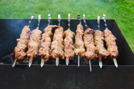 Photo for Barbecue meat on skewers cooking outdoors closeup - Royalty Free Image