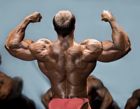 Photo for Mans back double biceps pose. Bodybuilder demonstrating arms on stage. Making opponents envious. One more step to victory. - Royalty Free Image