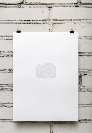 Foto de Cartel blanco en blanco contra una pared de ladrillo blanco. Disparo vertical
. - Imagen libre de derechos