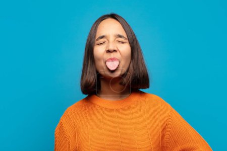 Photo for Hispanic woman with cheerful, carefree, rebellious attitude, joking and sticking tongue out, having fun - Royalty Free Image