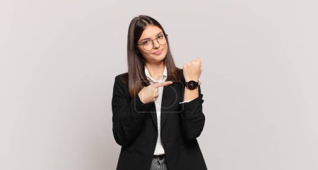 young business woman looking impatient and angry, pointing at watch, asking for punctuality, wants to be on time