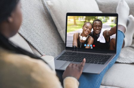 Concepto de comunicación digital. Jovencita teniendo videollamada con feliz pareja negra en el portátil desde casa