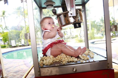 Photo for Beautiful little girl sitting in popcorn  machine  on the street - Royalty Free Image