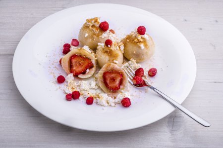 Foto de Fresas envueltas en masa a base de quark, servidas con quark desmenuzado, mantequilla derretida, fresas de bosque, azúcar morena y pan de jengibre finamente rallado - Imagen libre de derechos