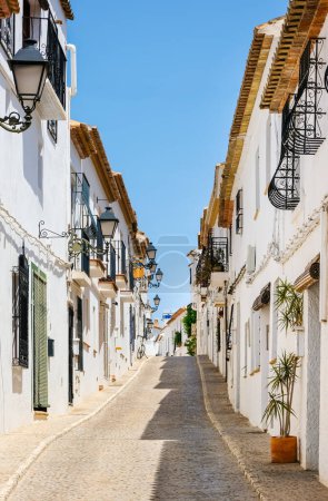 Típica vista del casco antiguo de Altea en España. Hermoso pueblo con calles estrechas adoquinadas, casas blancas típicas y linternas, popular destino turístico en la región de la Costa Blanca. Orientación vertical Típica vista del casco antiguo de Altea en España. Hermoso pueblo con calles estrechas adoquinadas, casas blancas típicas y linternas, popular destino turístico en la región de la Costa Blanca. Orientación vertical