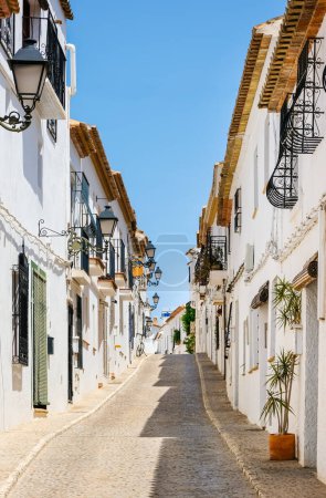 Foto de Típica vista del casco antiguo de Altea en España. Hermoso pueblo con empedrado calle estrecha, casas blancas típicas y linternas, destino turístico popular en la región de la Costa Blanca. Orientación vertical - Imagen libre de derechos