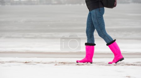 Téléchargez les photos : Femme en bottes en caoutchouc rouge marchant sur la neige - en image libre de droit