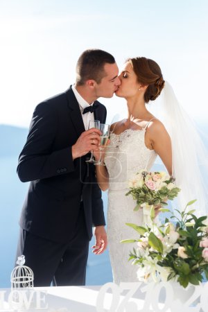 Photo for Newlywed couple drinking champagne at wedding aisle sea background - Royalty Free Image