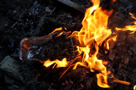 Plato de aluminio ardiendo en el fuego después de picnic en el bosque
