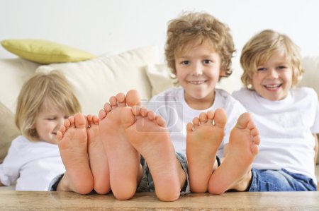 Foto de Tres chicos tienen sus pies sobre la mesa. - Imagen libre de derechos