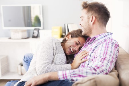 Atractiva pareja abrazándose en el sofá en casa en la sala de estar
Atractiva pareja abrazándose en el sofá en casa en la sala de estar