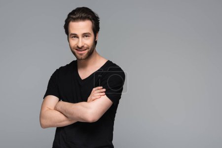 Photo for Cheerful bearded man in black t-shirt standing with crossed arms isolated on grey - Royalty Free Image