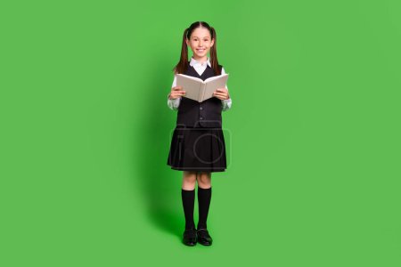 Vista completa del tamaño del cuerpo de la atractiva colegiala alegre libro de lectura aislado sobre fondo de color verde brillante Vista completa del tamaño del cuerpo de la atractiva colegiala alegre libro de lectura aislado sobre fondo de color verde brillante