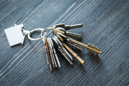 Photo for Bunch of keys with house shaped key ring on a rustic wooden table - Royalty Free Image