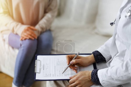 Téléchargez les photos : Gros plan de la femme-médecin et du patient discutant de l'examen de santé en cours pendant qu'ils sont assis à l'intérieur. Restez à la maison concept pendant la pandémie de coronavirus et auto isolement quarantaine. Covid 2019. - en image libre de droit