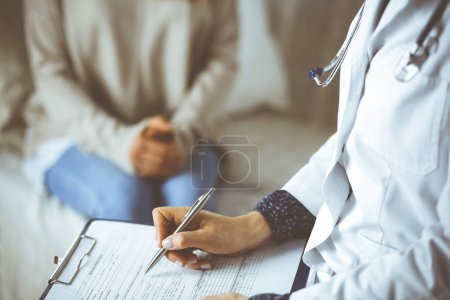 Mujer-médico desconocida y paciente discutiendo el examen de salud actual mientras está sentado en el interior. Permanecer en casa durante la pandemia de Coronavirus y la cuarentena de autoaislamiento