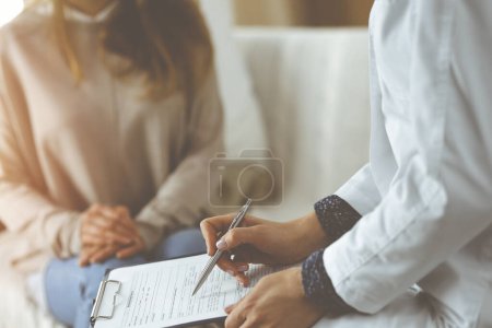 Primer plano de la mujer-médico y paciente discutiendo el examen de salud actual mientras está sentado en el interior. Permanecer en casa durante la pandemia de Coronavirus y la cuarentena de autoaislamiento. Covid 2019