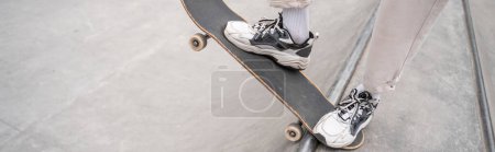 partial view of man in sport shoes riding skateboard on skate ramp, banner