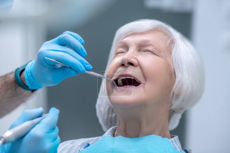 Dentiste en gants stériles travaillant avec un patient dans son bureau