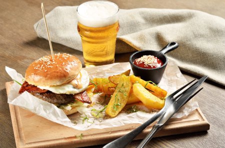 Hamburguesa, papas mexicanas y ketchup sobre tabla de madera
