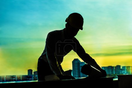 Photo for Architect looking  at blueprint. Successful young engineer in construction yellow helmet - Royalty Free Image