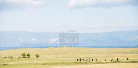 group of hikers going along horizon in mountains