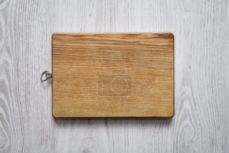 Wooden chopping board on brushed white table top view