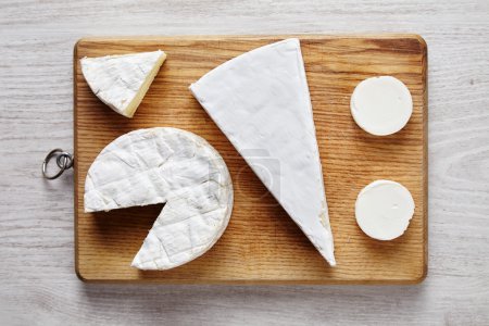 Quesos suaves blancos Avangard: cabra, brie, camembert sobre escritorio de madera
