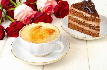 Piece of chocolate cake, cappuccino, flowers on table. Studio Photo