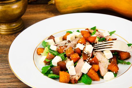 Foto de Ensalada con pollo, rúcula, calabaza caramelizada y queso Feta Estudio Foto - Imagen libre de derechos