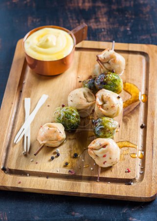 Téléchargez les photos : Dumplings et choux de Bruxelles sur brochettes avec sauce au fromage - en image libre de droit