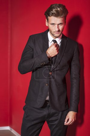 Hombre guapo en traje negro sobre fondo rojo
