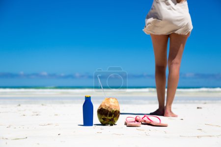 Photo for Young woman in a beautiful beach with coconut and sunblock in the foreground, Kenya, Africa. - Royalty Free Image