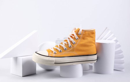 Escaparate de moda de elegante zapatilla de deporte amarilla y formas geométricas sobre fondo blanco. Arte conceptual Escaparate de moda de elegante zapatilla de deporte amarilla y formas geométricas sobre fondo blanco. Arte conceptual