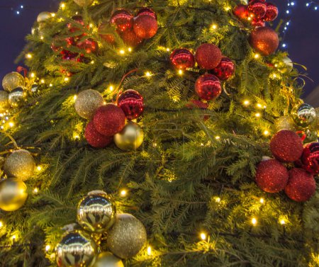 Foto de Primer plano desenfocado fondo de Navidad con ramas de abeto decoradas con bolas de vidrio y guirnalda eléctrica brillante. - Imagen libre de derechos