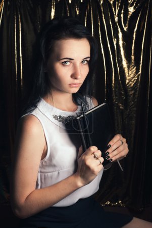 Foto de Chica en una blusa blanca, una joven estudiante con una varita mágica en la mano, linda morena modesta sobre el fondo dorado - Imagen libre de derechos