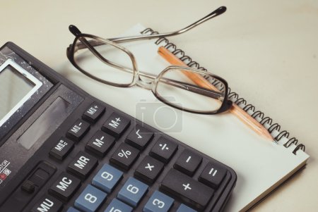 Foto de Calculadora, vasos y bloc de notas sobre la mesa, cuaderno de cuero, concepto de negocio - Imagen libre de derechos