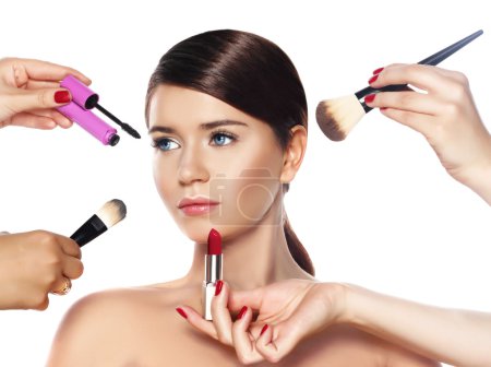 retrato de belleza de moda de hermosa joven sobre fondo blanco con una cara perfecta con muchas manos sosteniendo cepillo de maquillaje, lápiz delineador de ojos y lápiz labial aislado en blanco, estilo de moda

