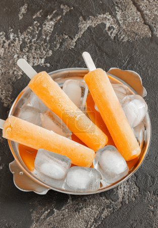 Delicioso helado de frutas en un palo en una placa de metal
