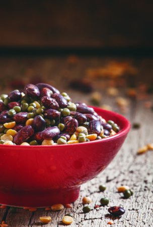 Photo for Bean mix: purple beans, green and red lentils, dry peas in a red bowl, vintage wooden background, selective focus - Royalty Free Image