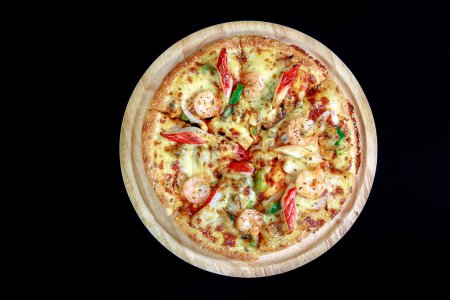 Photo for Top view of pizza on a wooden tray and on black background - Royalty Free Image