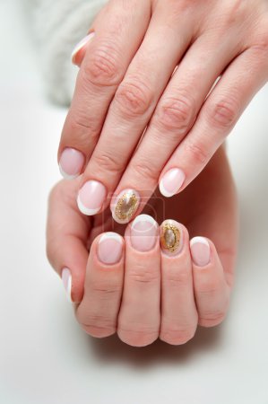 manicura francesa de boda con broche de camafeo de piedra líquida en el dedo anular
