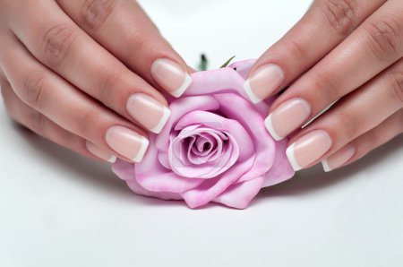 delicada manicura francesa con una rosa en la mano
