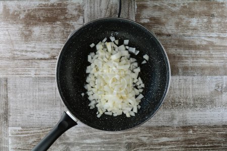 Foto de Preparación de cebolla en sartén sobre fondo de madera - Imagen libre de derechos